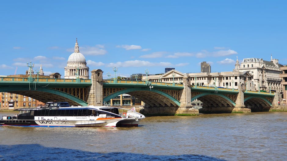 Nighttime view of the buildings along the River Thames near Blackfriars Bridge in London, featuring the illuminated Blackfriars Millennium Bridge in the foreground, with reflections on the water surfa